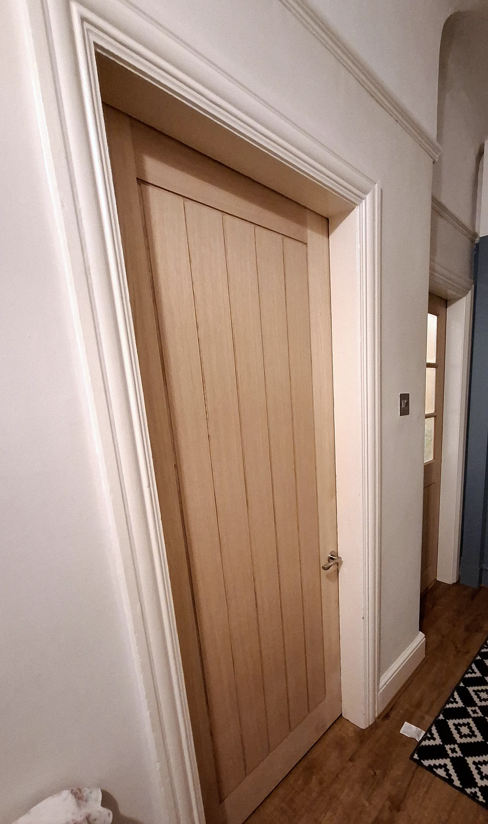 Oak cottage-style internal door hung in a hallway with new white architrave